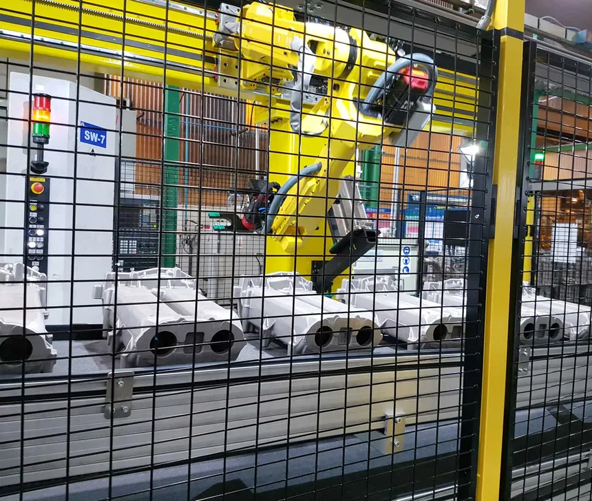 Robot industrial dentro de celda con conveyor y manejo de piezas